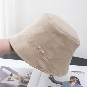 Detailed view of beige cotton bucket hat texture with a premium leather logo patch
