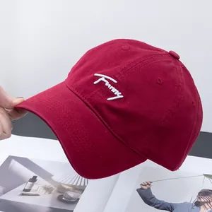 Detailed close-up of white 'Funny' embroidery on dark red cotton canvas baseball cap