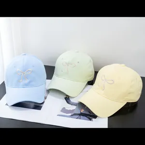 Detailed view of pastel blue green and yellow baseball caps with bow embroidery