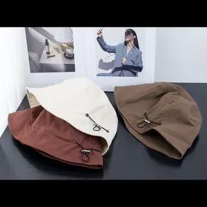 Adjustable drawstring buckles on neutral toned cotton bucket hats in beige and brown