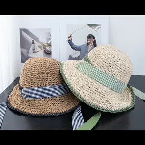 Detail of hand-woven straw hats with plaid ribbons for summer beach sun protection