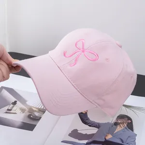Close-up of pink baseball cap featuring delicate dark pink bow embroidery and cotton texture