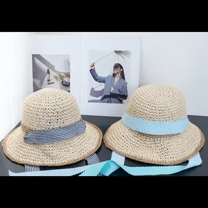 Detailed close-up of handmade woven straw hats with black and blue gingham ribbon ties