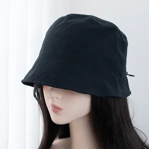 Detail of a black cotton bucket hat with an adjustable drawstring on a side profile