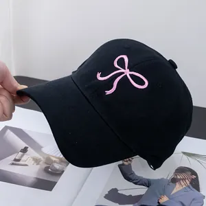 Close-up of pink bow embroidery on a black cotton baseball cap with high texture
