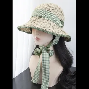 Detail of summer straw hat featuring green gingham ribbon and delicate woven edge
