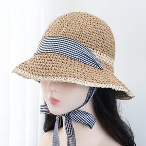 Detailed close-up of handmade straw hat with black and white gingham ribbon tie