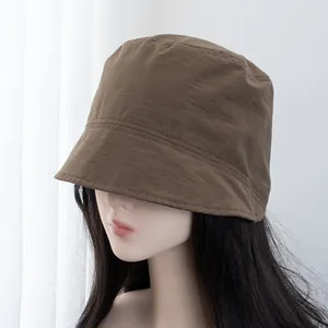 Detail view of brown short-brim bucket hat showing nylon texture and fine stitching lines