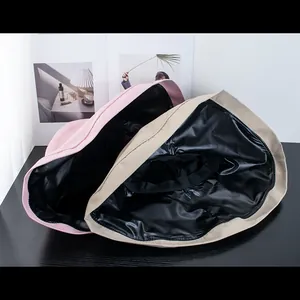 Pink and khaki wide brim sun hats with black glue interior lining on dark wood