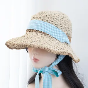 Detailed close-up of light beige straw hat weave and blue gingham ribbon ties