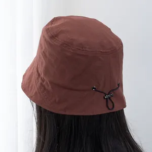 Detail of adjustable drawstring with toggle on a brown short brim sun bucket hat