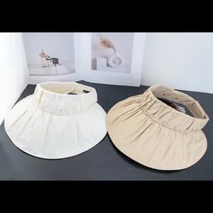 Detail view of cream and beige wide brim sun visors with pleated fabric texture
