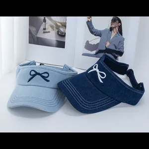 Close-up of denim sun visors in light and dark blue with embroidered bow detail
