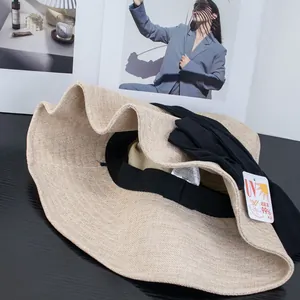 Women's foldable UV protection sun hat with large bow on dark wood background