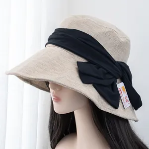 Detail of beige sun hat with large black bow and UV protection tag on side