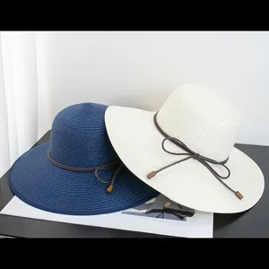 Detail of wide-brim woven sun hats with ribbon bow in navy and cream white colors