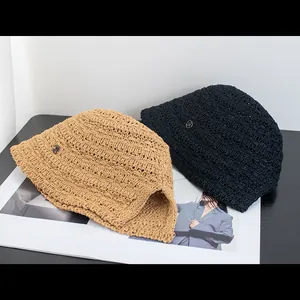 Dettaglio di cappelli di paglia intrecciati con logo metallico e trame in maglia fitta
