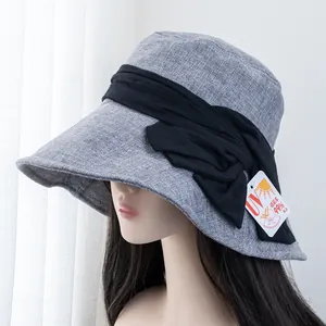 Detailed side view of grey sun hat with black bow and 99% UV protection tag