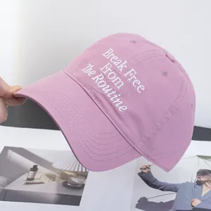 Close-up of white embroidery slogan on dusty pink cotton canvas baseball cap