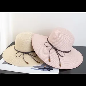 Foldable women's wide brim straw sun hats in beige and pink with decorative bow ties