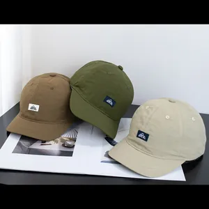 Détail de casquettes en nylon à séchage rapide marron, olive et beige avec écusson montagne