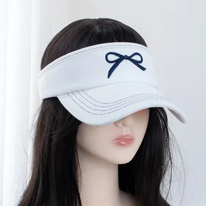 Detail of embroidered navy bow on a white denim sun visor with decorative stitching