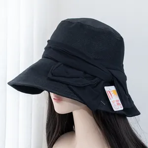 Detail of wide brim sun hat with bow showing UV 99% protection tag on breathable fabric