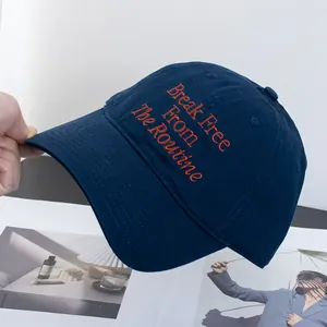 Detail of embroidered orange text on navy cotton twill baseball cap with soft top