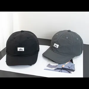 Détail de casquettes de baseball à séchage rapide avec écusson logo OY.X en noir et gris