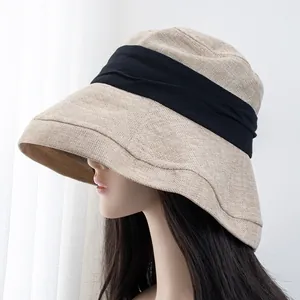 Detail of the coarse woven texture and wide black ribbon on a khaki wide-brim sun hat