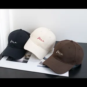Detailed embroidery of cursive me letters on minimalist cotton baseball caps