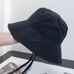 Detail of a black bucket hat showing triangular stitching and adjustable chin strap