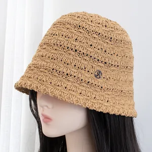 Dettaglio della maglia di un cappello da sole beige con un emblema logo A in metallo