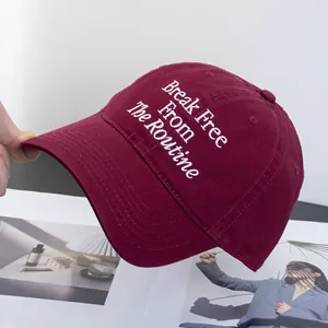 Detailed close-up of white embroidery text on a premium burgundy cotton baseball cap