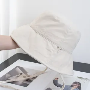 Detail of a light beige sun hat with herringbone stitching and adjustable drawstring