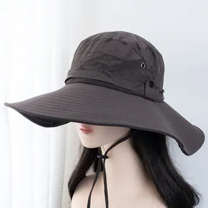 Détail d'un chapeau de soleil marron foncé à large bord avec œillets et boutons-pression