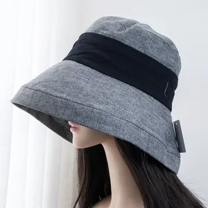 Detailed view of gray woven linen sun hat with black decorative ribbon and wide brim