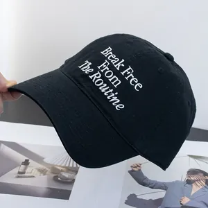 Detailed close-up of Break Free From The Routine white embroidery on a black cotton baseball cap