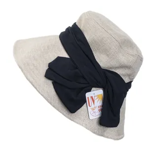Women's UV protection sun hat in beige with a large black ribbon bow and foldable design