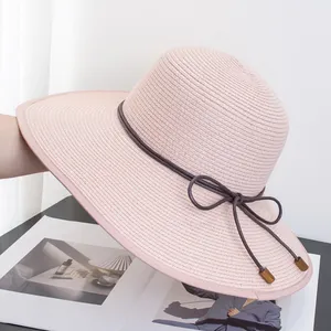 Detail of light pink straw hat featuring fine weave and brown leather cord with wood bead