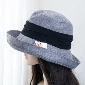 Detail showing the UV protection tag and grey linen texture of the wide-brim sun hat