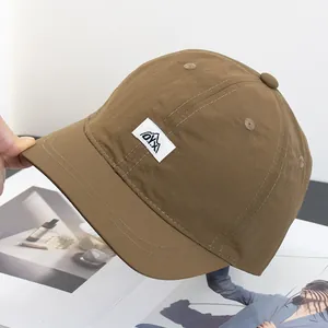 Détail d'une casquette marron à bord court avec écusson logo montagne sur un magazine