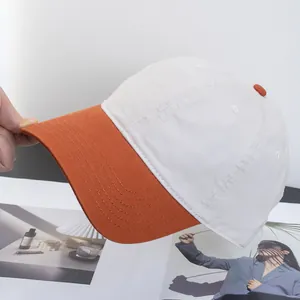 Detail der weißen und orangen Baumwoll-Baseballkappe mit Belüftungsösen und Kontrastschirm