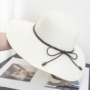 Close-up of woven paper straw texture on cream sun hat with brown decorative rope trim
