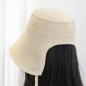 Detailed close-up of beige knitted straw sun hat with wide brim and adjustable side ribbons