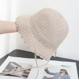 Detailed view of hand-woven cream sun hat with scalloped edges and adjustable ribbon straps