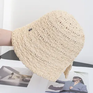 Dettaglio della trama del cappello di paglia intrecciata con logo metallico sul lato
