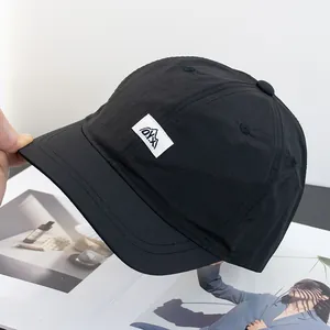 Gros plan sur la casquette noire à bord court avec patch logo montagne et tissu nylon