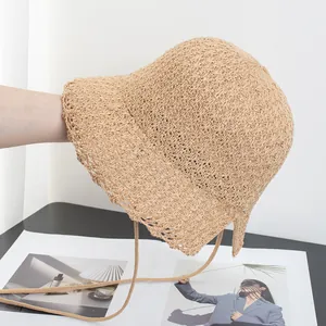 Detail of hand-woven straw bucket hat with adjustable chin strap in beige