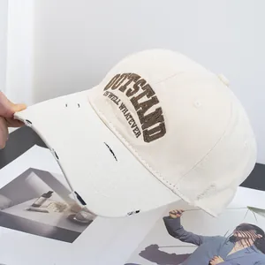 Detailed embroidery of OUTSTAND letters on a distressed cotton baseball cap
